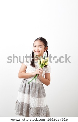 Asian little girl holding a bouquet of yellow tulips on white background. Concept of holidays