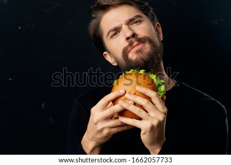 Black background man with a hamburger puzzled look