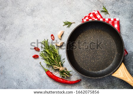 Food cooking background with Frying pan or skillet, spices and herbs on gray stone table. Top view with copy space. Royalty-Free Stock Photo #1662075856