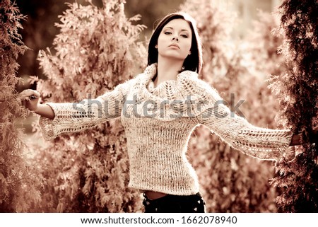 Monochrome photo of a beautiful young serious girl in casual clothes sitting on a zone in a park on a sunny autumn day. Femininity concept