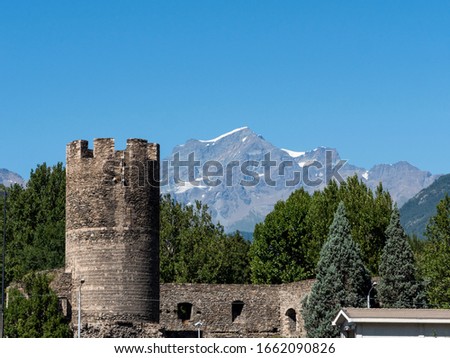 Tower of the ancient castle at the background of the Alps.