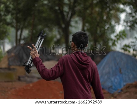 Rear photo of a boy,Holding a tripod.Photographer with tripod going home after a pack up of photo shoot