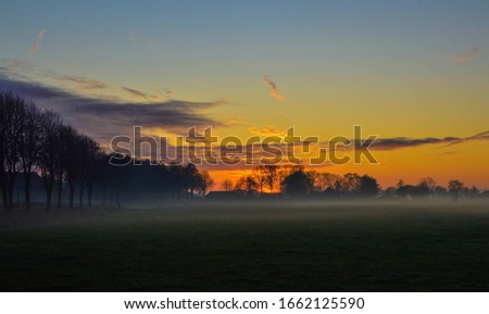 Beautiful sunset lights up sky over misty meadow, landscape of a field near Oldemarkt, The Netherlands, Europe