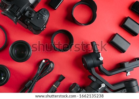 Flat lay composition with camera and video production equipment on red background