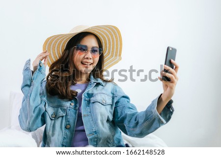 pretty woman traveler shooting selfie and choosing fashion hat prepare packing clothes into suitcase for holiday vacation at home, long weekend, summer holiday, vacation, backpacker and travel concept