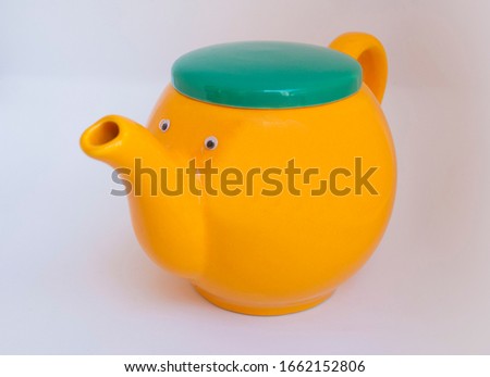 Yellow good mood teapot with face. Creative photo idea.