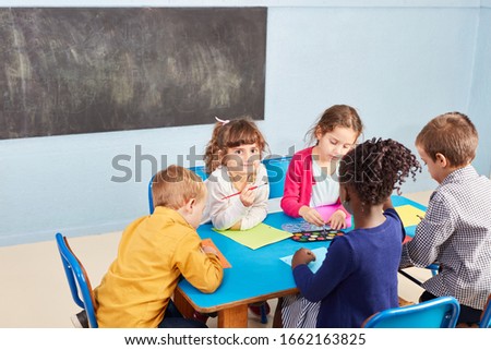 Children paint in the kindergarten with watercolors and paintbrushes at the table