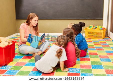 Group of children and educator reading a children's book in kindergarten