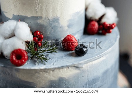 winter grey icing birthday wedding cake decorated with cotton flowers and berries 
