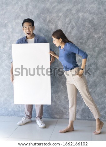 Happy Asian couple present blank white board with gray backbround.