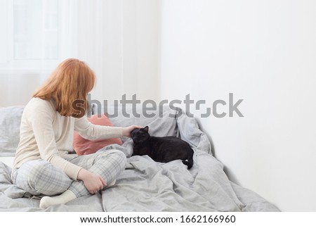 teenager girl with black cat on bed at home
