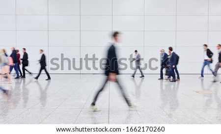 Many blurry anonymous business people go by airport or conference