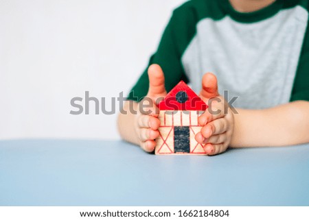 Wooden house in little children's hands on the table.Home owning concept