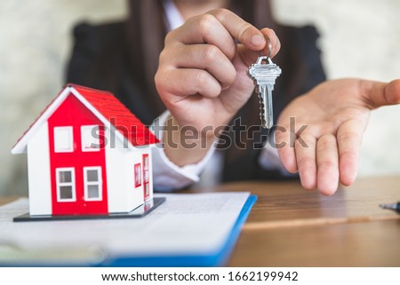 Close-up of real estate agents holding house keys for clients. Ideas for real estate business, moving houses or renting real estate, business people holding the keys for buying and selling homes.