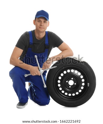 Portrait of professional auto mechanic with wheel and lug wrench on white background