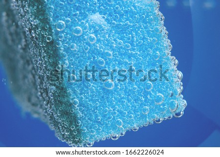 blue dishwashing sponge, selective focus. bubbles, under water. porous macro sponge
