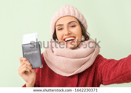 Female tourist with documents taking selfie on color background