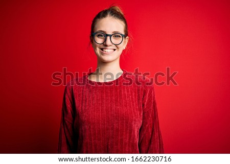 Young beautiful redhead woman wearing casual sweater over isolated red background with a happy and cool smile on face. Lucky person.