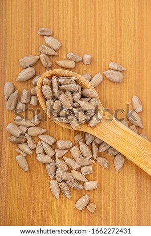 Spoon of stick and sunflower seeds on wooden background.