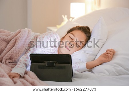 Cute little Asian girl sleeping in bed after watching cartoons