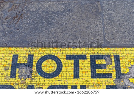 Damaged Hotel Sign Mosaic Tiles at Pavement