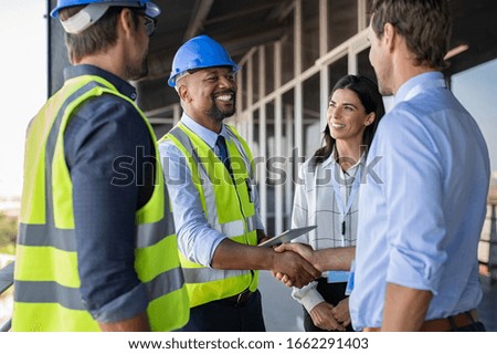Smiling engineer shaking hands at construction site with happy architect. Handshake between african construction manager with businessman at bulding site. Team of workers conclude an agreement. Royalty-Free Stock Photo #1662291403