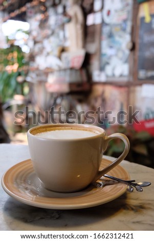 Hot cappuccino in a white coffee mug on a marble table in a coffee shop.Photo not focus.