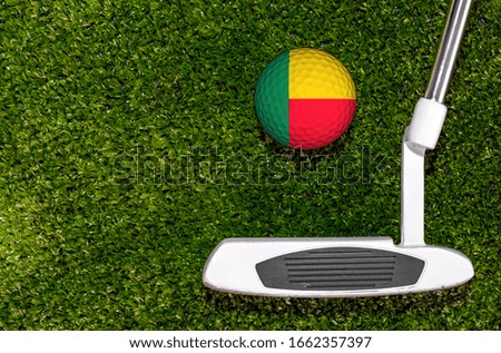 A golf club and a ball with flag Benin during a golf game.