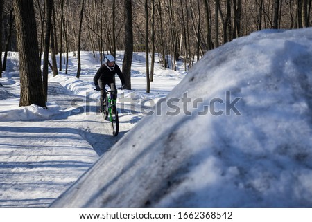 
A cyclist in a helmet rides on a pump track in winter. Mtb rider rides a bike on a snowy track