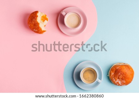 Breakfast backdrop with two cups of coffee and homemade freshly baked doughnuts on a duotone pastel pink blue background.