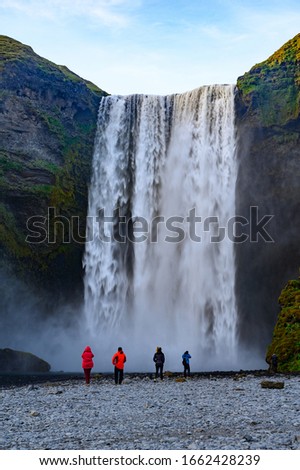 Tourists taking photos near powerfull Skogafoss waterfall in Iceland
