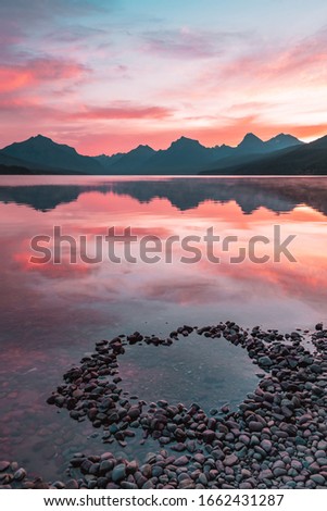 A heart made of stones on the edge of Lake McDonald with a vibrant colorful sunrise in Glacier National Park, Montana, USA. Royalty-Free Stock Photo #1662431287