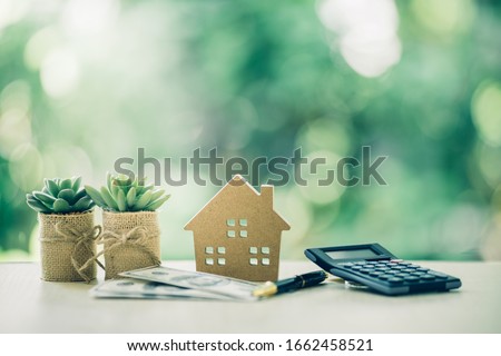 Property investment concept. Wooden house, dollar bill and calculator on table. Pen prepare planning savings money to buy a home, mortgage and real estate investment.