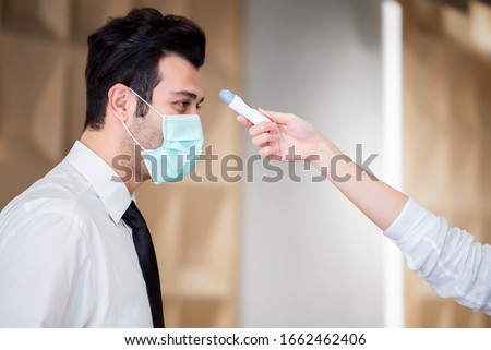 Operator Check Fever by Digital Thermometer Visitor at Information Counter for Scan and Protect from Coronavirus (COVID-19) Royalty-Free Stock Photo #1662462406