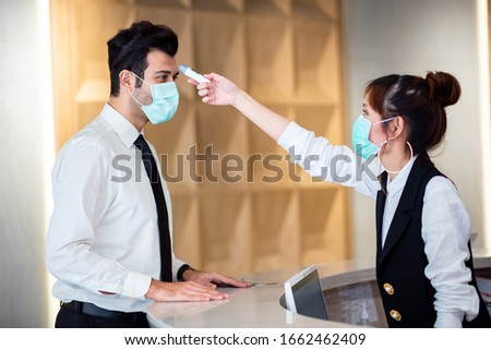 Operator Check Fever by Digital Thermometer Visitor at Information Counter for Scan and Protect from Coronavirus (COVID-19) Royalty-Free Stock Photo #1662462409