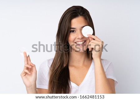 Teenager girl over isolated background with cotton pad for removing makeup from her face and smiling Royalty-Free Stock Photo #1662481153