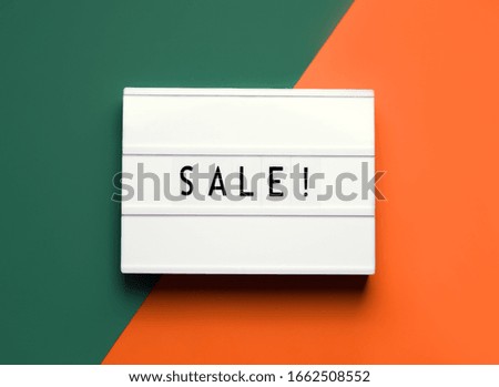 lightbox white board with sale inscription on a green and orange background