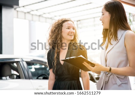 The Asian woman salesperson talking and explaining about insurance to a smiling and happy Caucasian woman client before hand over a new car. Automotive Leasing and Dealing Business. 