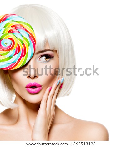 Surprised face of an young pretty woman  with bright red hairs and multicolor nails.  Studio photo.