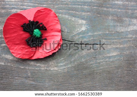 USA Memorial Day concept of red remembrance poppy selfmade from fabric on dark vintage distressed wooden background, with copy space.