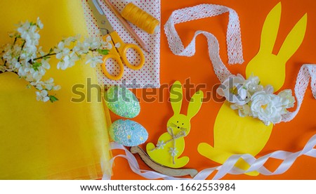 Easter craft paper yellow rabbit on an orange background. Pattern from paper for a pattern and sewing from fabric of an Easter rabbit. Easter accessories and decorations