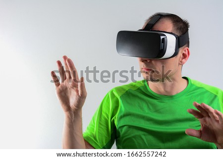 Excited man experiencing virtual reality via VR headset and touching something with his hands isolated on white background