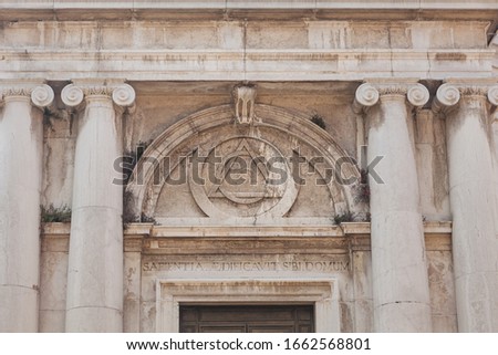 Massonic eye sign inside triangle on building of Church of St. Magdalena, Canaregio District, Venice, Italy. Text on portal above entrance in Latin means: Wisdom has built a house