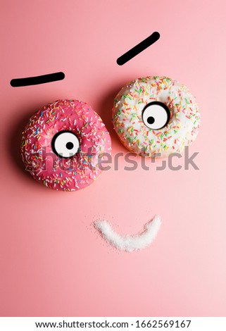 
funny smiley of two donuts and sugar on a pink background with place for text, an example of junk food