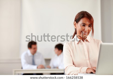 Portrait of an adult executive woman looking at her laptop while sitting on office desk - copyspace