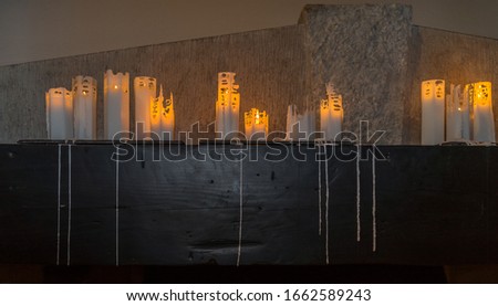 Decorative ornamental candles on the fireplace mantelpiece. Melting wax stripes on heavy wooden basement. Warm light of burning candle in the darkness, showing the way. Estonia.