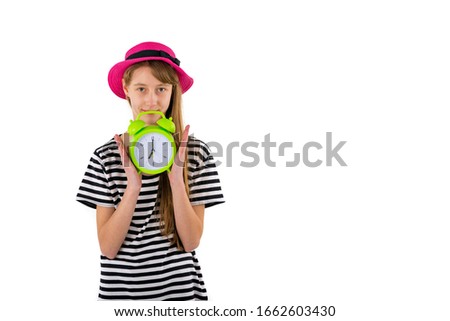 Amazed slim mysterious teenage girl holding clock. Girl in white black striped t-shirt holds alarm clock.  Saving time concept. Summer sale. Discount. Isolated on white background.