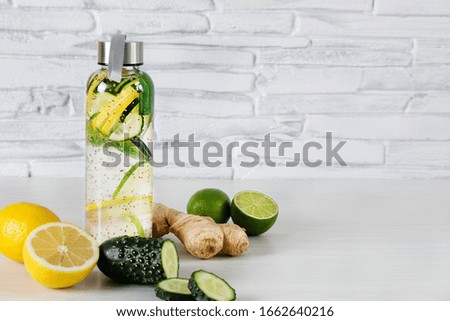 Detox infused water with lemon, lime, ginger and cucumber in a glass sport bottle on white wooden background over brick wall. Detoxification. Healthy eating concept. Royalty-Free Stock Photo #1662640216