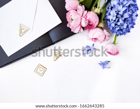 Flowers composition and black notebook. Gift and pink ranunculus blue hyacinth flowers on white background. Place for your design. Flat lay, top view, overhead.