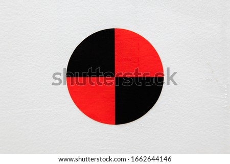 Round sign on a white background with black-red symmetrical triangles inside.